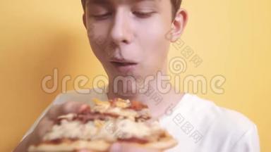 快乐的小男孩吃一片披萨的概念。 饥饿的青少年男孩吃一片披萨。 慢速视频